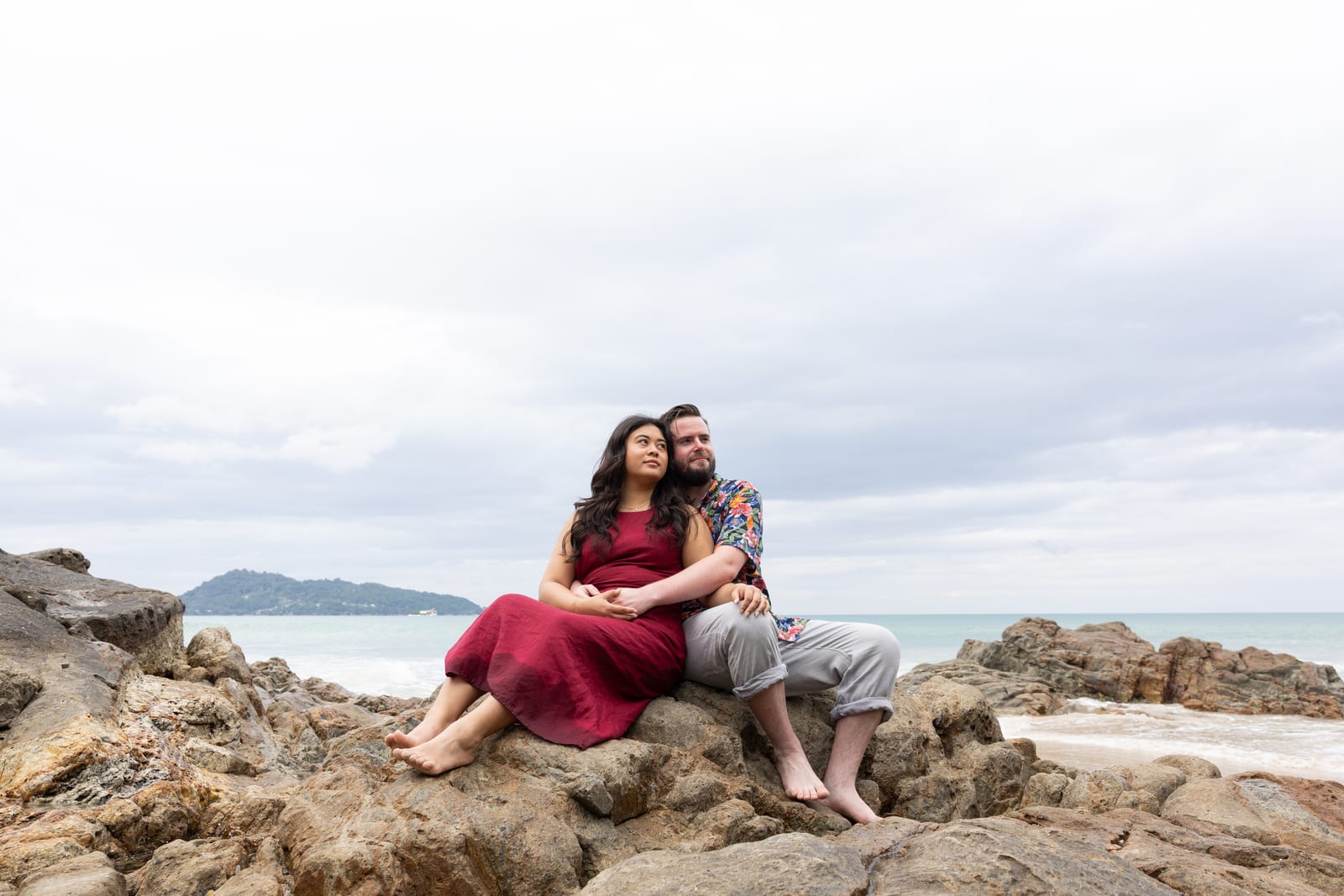 Lauren and Hunter sitting together on beach rocks by the sea