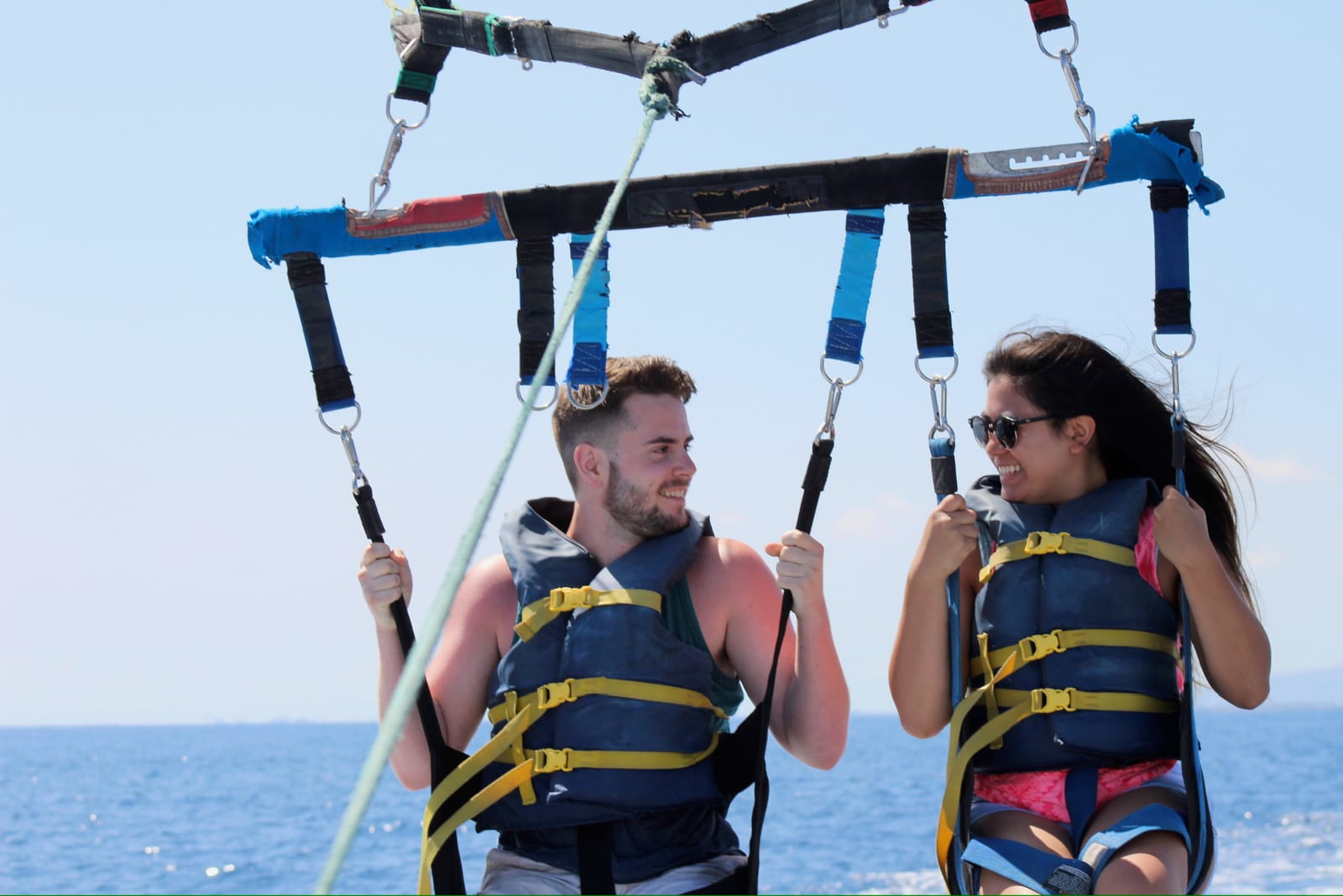 Laughing together in parasailing harnesses over the water